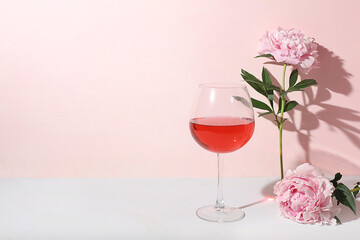 Modern still life with rose wine, alcoholic cocktail and peony flowers on pastel background with long hard shadows, minimal concept for bar, cafe, advertising banner, selective focus, space for text