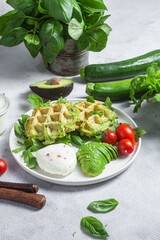 Zucchini waffles, poached egg, avocado and cherry tomatoes in a plate