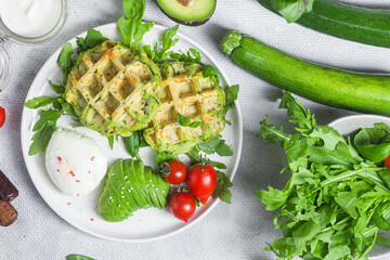 Zucchini waffles, poached egg, avocado and cherry tomatoes in a plate