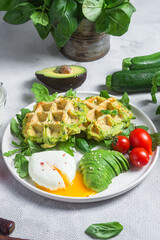 Zucchini waffles, poached egg, avocado and cherry tomatoes in a plate