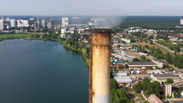 Old rust industrial factory chimney with smoke emission. City river pollution concept.