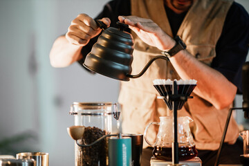 Barista making drip coffee with hot water being poured from a kettle, Ground coffee beans contained in a filter, Make drip coffee, Slow bar coffee.