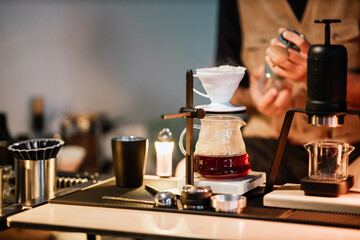 Barista making drip coffee with hot water being poured from a kettle, Ground coffee beans contained in a filter, Make drip coffee, Slow bar coffee.