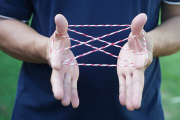 Closeup man hands is playing rope which called cats cradle game. Concept, game involving the...