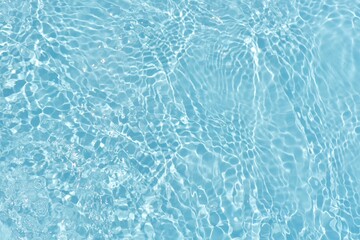 Blue water with ripples on the surface. Defocus blurred transparent blue colored clear calm water surface texture with splashes and bubbles. Water waves with shining pattern texture background.