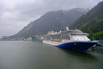 Modern cruiseship cruise ship liner Spirit docked at terminal in Juneau, Alaska during heavy rain and low cloud nature scenery with mountains and foggy misty atmosphere