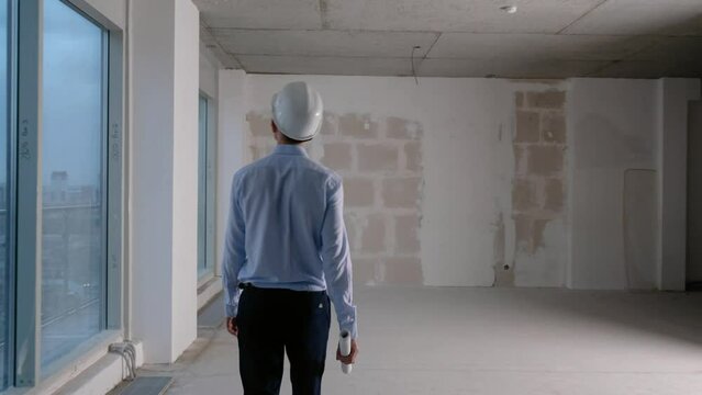 Young man working as engineer in new apartment buildings, looking at building plan in construction site