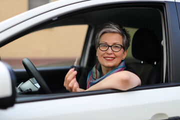 Portrait of a woman in a rental car with keys in her hands.