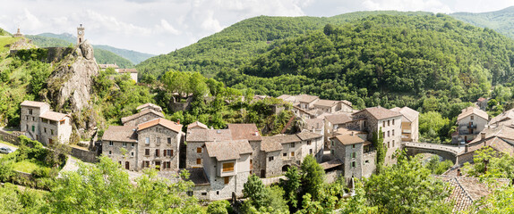 Panorama d'un joli vieux village dans une vallée encaissée de montagnes verdoyantes depuis un point haut. Burzet en Ardèche