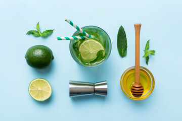 Caipirinha, Mojito cocktail, vodka or soda drink with lime, mint and straw on table background. Refreshing beverage with mint and lime in glass top view flat lay