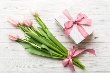 Pink tulips flowers and gift or present box on colored table background. Mothers Day, Birthday, Womens Day, celebration concept. Space for text top view