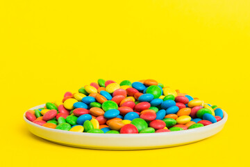 Multicolored candies in a bowl on a colored background. birthday and holiday concept. Top view with copy space