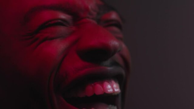 Man laughing reacting to something on the big screen while face lights up with colour