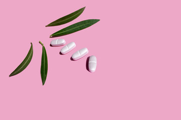 pink pills, flowers and pill box on a pink background