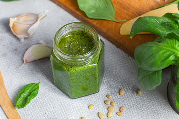 Pesto sauce in a glass jar on the table. Basil