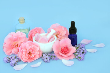Rose and lavender flower aromatherapy essence with pink flowers on blue.  Natural floral alternative herbal medicine to treat skin problems, insomnia, anxiety and promote relaxation.