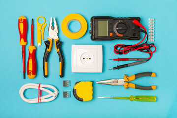 Electrician equipment on blue background with copy space.Top view.Electrician tool set.Multimeter, tester,screwdrivers,cutters,duct tape,lamps,tape measure and wires.Flet lay. © Avocado_studio
