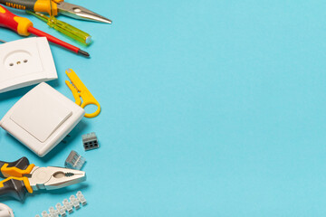 Electrician equipment on blue background with copy space.Top view.Electrician tool set.Multimeter, tester,screwdrivers,cutters,duct tape,lamps,tape measure and wires.Flet lay. © Avocado_studio