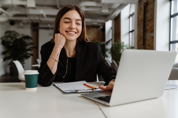 Cheerful business woman working on laptop in office