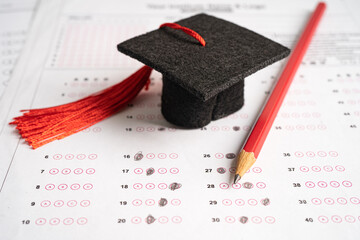 Graduation gap hat and pencil on answer sheet background, Education study testing learning teach...