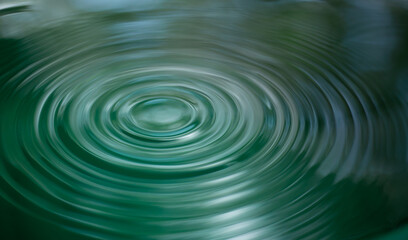 Ripple of water or water drop splash on green nature background. Abstract shape out of the water