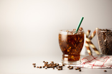 Iced americano coffee with coffee beans on grey background, Glass of black coffee, Beverage at coffee shop.