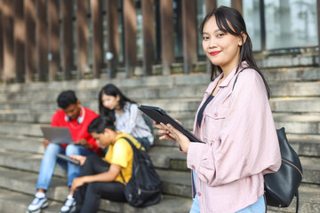 Happy university student going on a class at the university and looking at camera.