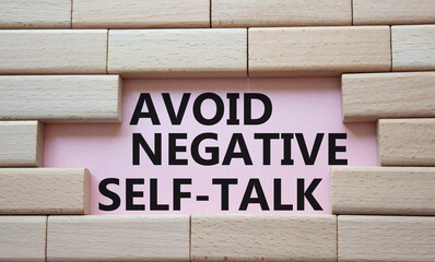 Avoid negative self-talk symbol. Concept words Avoid negative self-talk on wooden blocks. Beautiful pink background. Business and Avoid negative self-talk concept. Copy space.