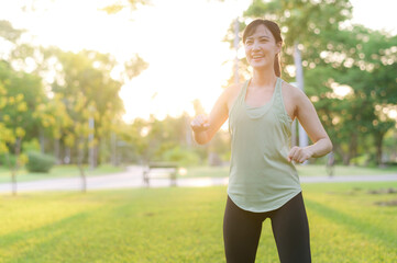 Female jogger. Fit young Asian woman with green sportswear stretching muscle in park before running and enjoying a healthy outdoor. Fitness runner girl in public park. Wellness being concept