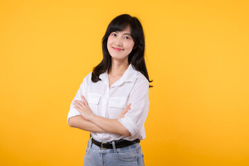 Young Businesswoman. Portrait asian woman happy smiling, posing confident, cross arms on chest, standing against yellow studio background. Smart young entrepreneur advertising products and services.