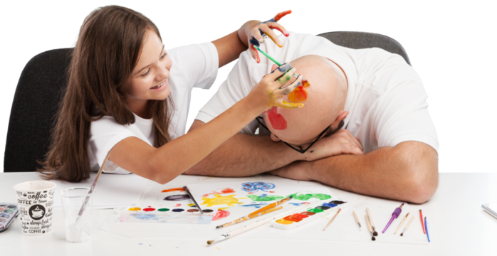 Painting concept. Schoolgirl painting with father during therapy at home with his tutor with learning and having fun together.
