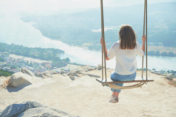 Relax and enjoy life concept. Young woman swings on a rope swing placed on a mountain in Vila Nova...