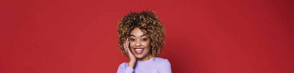 Young black woman with afro curls smiling and posing at camera