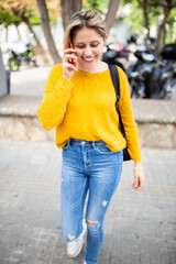 Attractive young woman walking outside talking on mobile phone