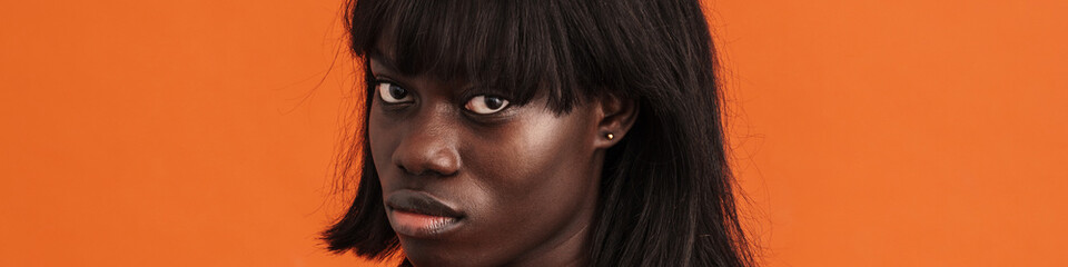 Serious african lady demonstrates refusal sign isolated over orange background