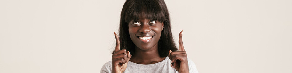 Young beautiful smiling african woman with bob haircut pointing up