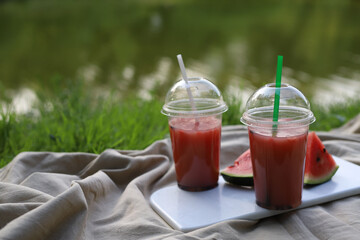on a summer picnic on a white board on the shore of the lake, a watermelon cocktail stands in transparent glasses and straws for drinking and next to slices of ripe juicy tasty watermelon