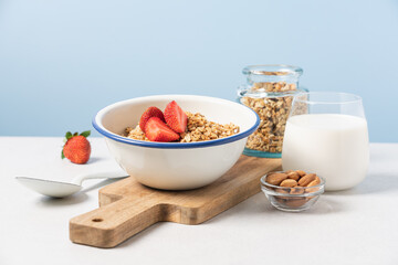 Granola in bowl with strawberries on blue background with copy space. Food breakfast background
