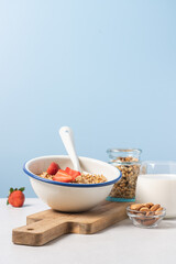 Granola in bowl with strawberries on blue background with copy space. Food breakfast background