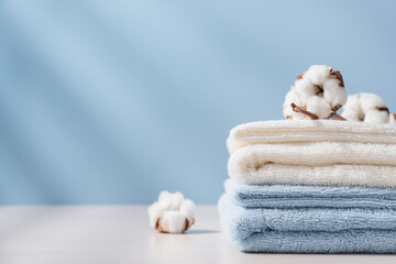 Stack of organic cotton terry towels on blue background with copy space. Delicate textiles, bath accessories - obrazy, fototapety, plakaty