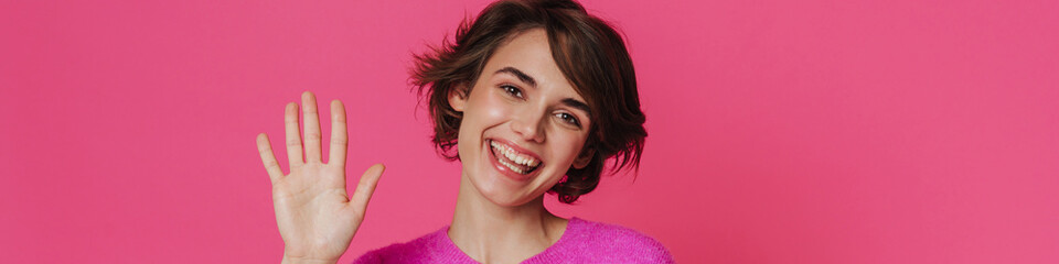 White young woman wearing sweater smiling and waving hand