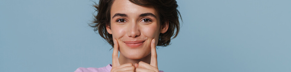Obraz premium White excited woman wearing t-shirt pointing fingers at her cheek