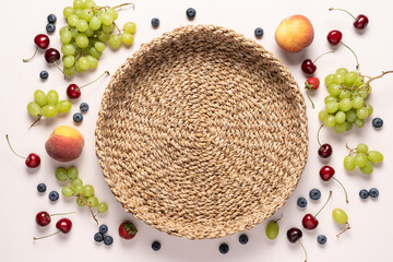 Empty wicker tray with berries and fruits around. Frame Food background top view