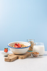 Obraz na płótnie Canvas Granola in bowl with strawberries on blue background with copy space. Food breakfast background