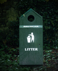 green litter bin in park with gaelic text