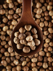 Peeled hazelnuts in close-up with wooden spoon. View from above. Promotional photo of healthy nut for online store and marketplaces.