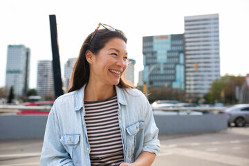 Smiling asian woman looking away walking outside in the city