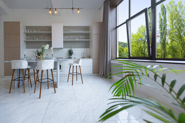 close view kitchen with dinning marble table and hight bar stools in minimalistic light elegant luxury design of a modern spacious studio apartment in soft pastel beige colors