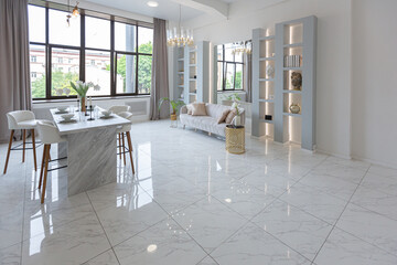 minimalistic light elegant luxury design of a modern spacious studio apartment with kitchen area, bedroom and huge mirror behind the couch. tiles on the floor and high ceiling.