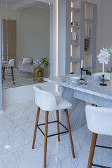 close view kitchen with dinning marble table and hight bar stools in minimalistic light elegant luxury design of a modern spacious studio apartment in soft pastel beige colors